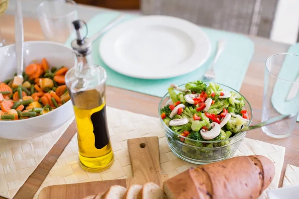 Skål med sallad och olivolja på matsal bord — Stockfoto