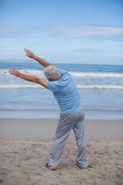 Ανώτερος άνθρωπος κάνει τεντώνοντας άσκηση στην παραλία — Φωτογραφία Αρχείου