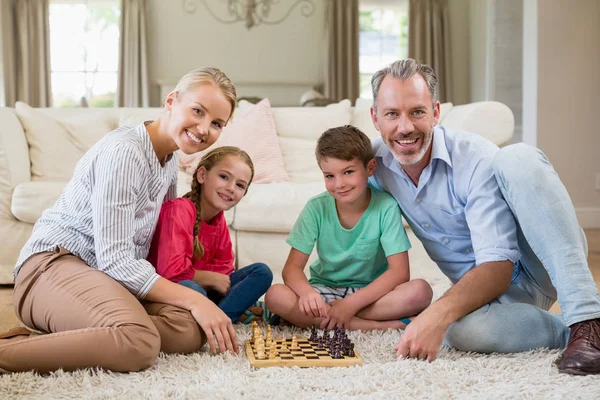 Família jogando xadrez juntos em casa na sala de estar — Fotografia de Stock