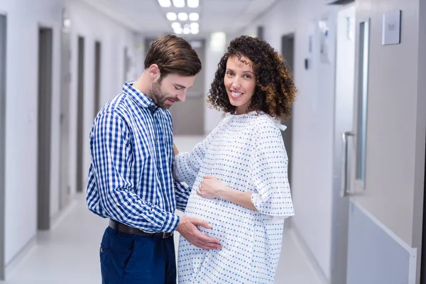 Muž uklidňující těhotná žena v chodbě — Stock fotografie