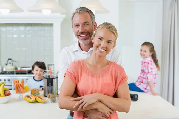 Paar umarmt sich, während Kinder im Hintergrund lächeln — Stockfoto