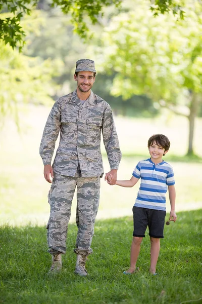 Porträt eines Armeesoldaten, der seinem Sohn im Park die Hand hält — Stockfoto