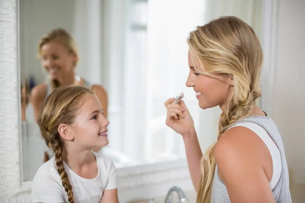 Mutter interagiert mit Tochter, während sie Lippenstift im Badezimmer aufträgt — Stockfoto