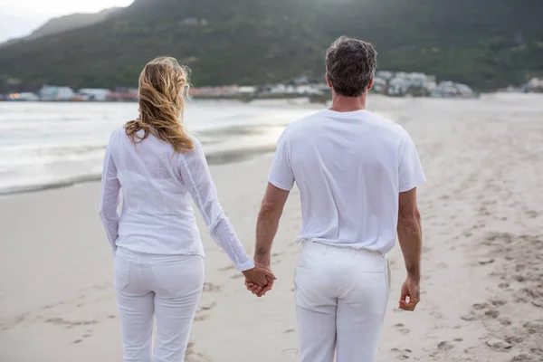 Casal de pé com as mãos dadas na praia — Fotografia de Stock