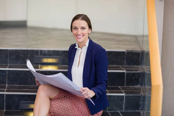 Zakenvrouw zittend op stappen houden blauwdruk — Stockfoto