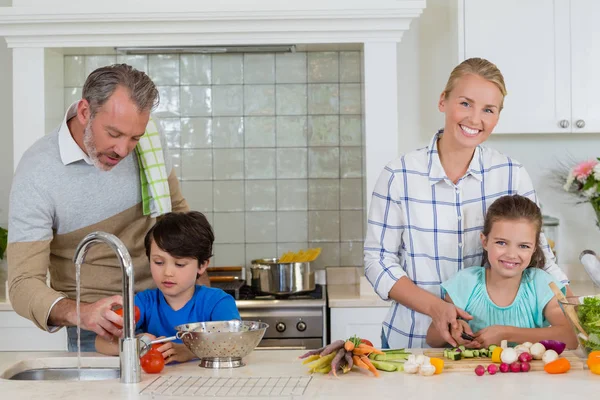 Les parents aident un enfant à couper et nettoyer les légumes dans la cuisine — Photo