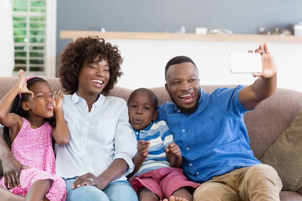 Família feliz tirando uma selfie do celular na sala de estar — Fotografia de Stock