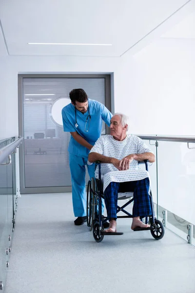Врач, взаимодействующий с пожилым мужчиной в инвалидном кресле — стоковое фото