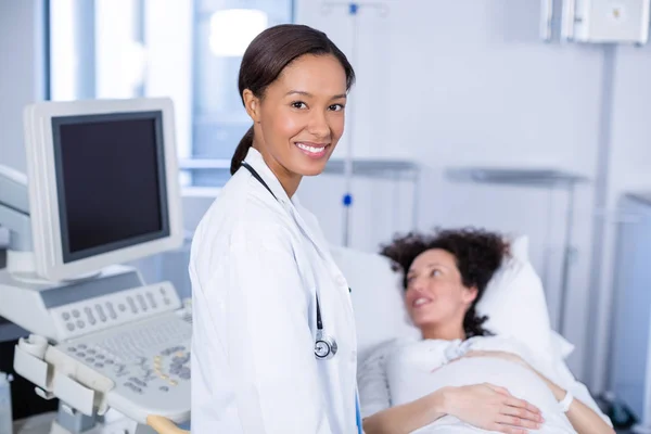 Retrato del médico sonriente haciendo ecografía para la mujer embarazada — Foto de Stock