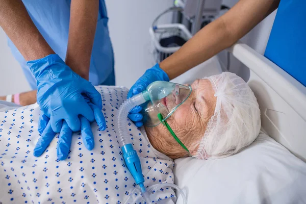 Médico e enfermeiro tratando paciente idoso na enfermaria — Fotografia de Stock