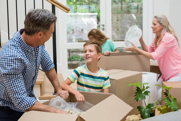Padres y niños desempacando cajas de cartón en la sala de estar —  Fotos de Stock