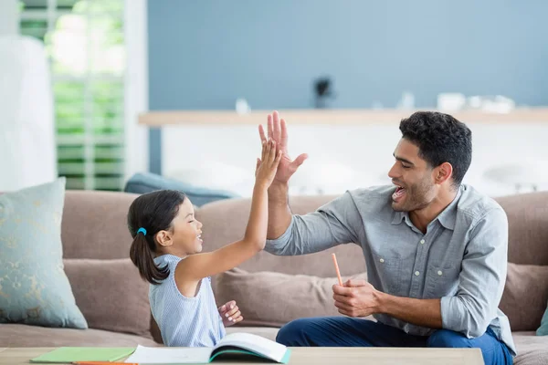 Vader geven hoge vijf aan dochter terwijl het helpen van haar in huiswerk — Stockfoto