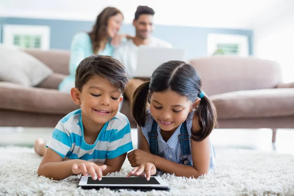 Kardeşler halı oturma odasında yatan ise dijital tablet kullanma — Stok fotoğraf