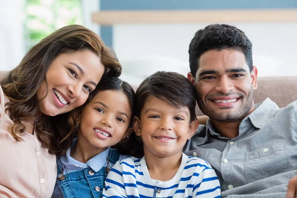 Retrato de padres felices y niños sentados en el sofá en la sala de estar —  Fotos de Stock