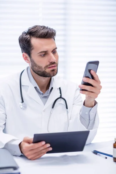 Médecin masculin utilisant un téléphone portable tout en tenant tablette numérique — Photo