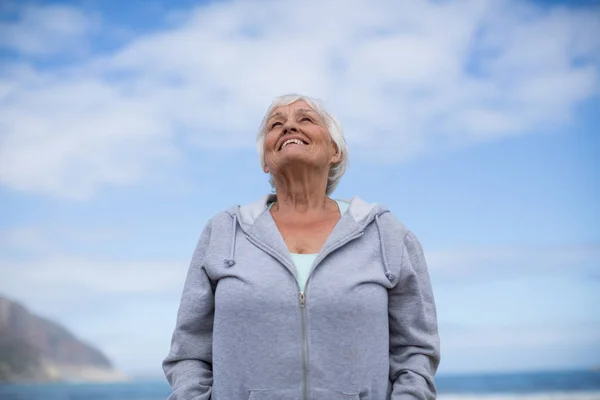 Senior mulher de pé na praia — Fotografia de Stock