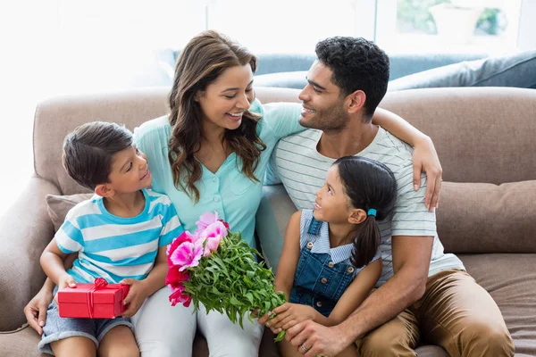 Ouders en kinderen interactie op sofa met presenteren in woonkamer — Stockfoto