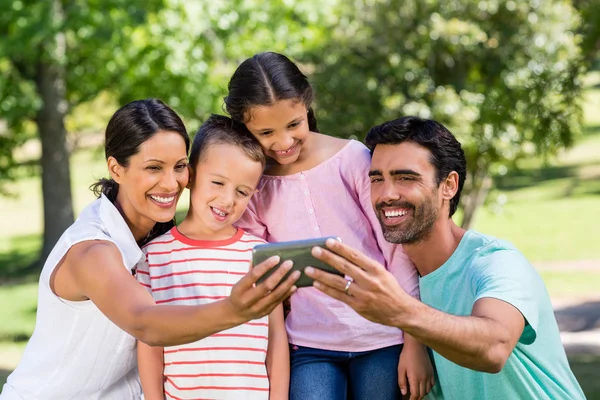 Szczęśliwa rodzina biorąc selfie z telefonu komórkowego w parku — Zdjęcie stockowe