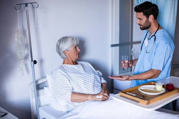 ベッドの上の女性先輩患者に医療を提供する医師 — ストック写真