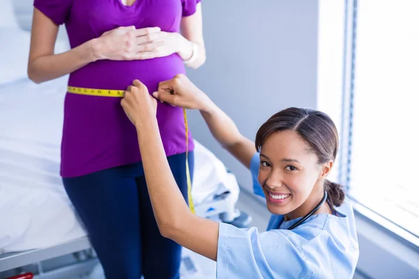 Портрет врача, измеряющего животик беременной женщины в палате — стоковое фото