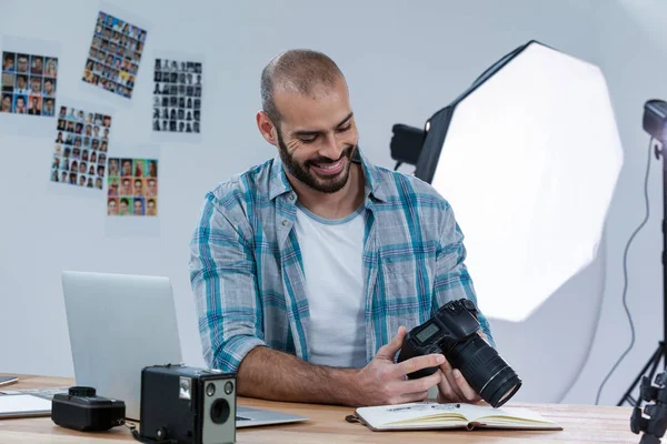 Fotógrafo masculino revisando fotos capturadas en su cámara digital — Foto de Stock