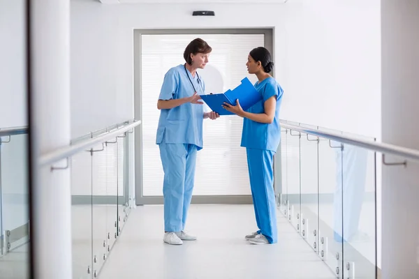 Nurse and doctor discussing over clipboard — Stock Photo, Image