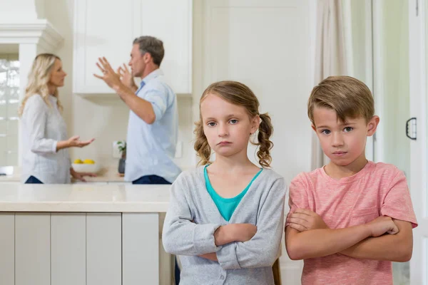 Triest sibling permanent met gekruiste terwijl ouders ruzie elkaar armen — Stockfoto