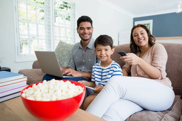 Matka, sledování televize, zatímco otec a syn pomocí přenosného počítače a digitální tabletu doma — Stock fotografie