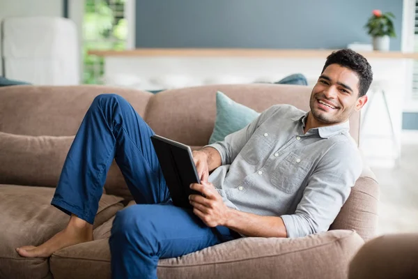 Uomo sdraiato sul divano e utilizzando tablet digitale in soggiorno a casa — Foto Stock
