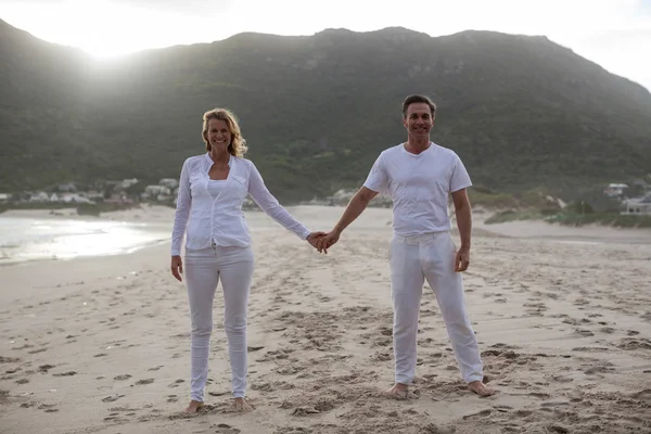 Пара стоящих и держащихся за руки на пляже — стоковое фото