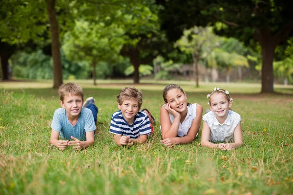 Šťastné děti leží na trávě — Stock fotografie