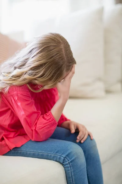 Smutna dziewczyna siedzi na kanapie w salonie — Zdjęcie stockowe