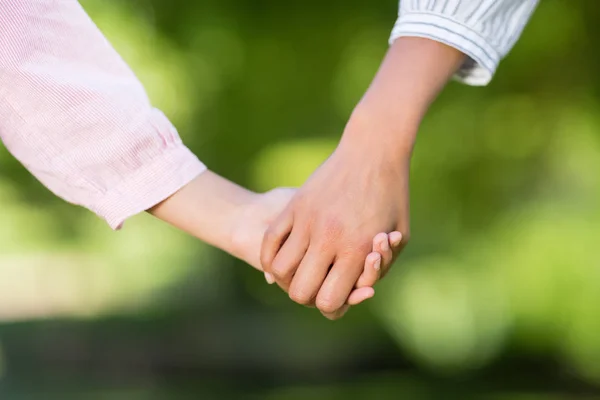 Mother holding hands of her daughter in park — Stock Photo, Image