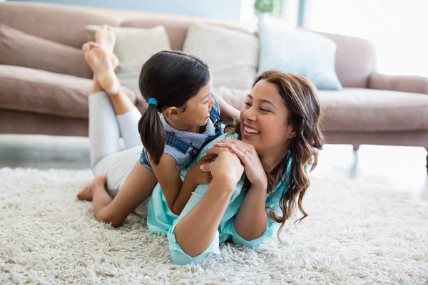 Feliz hija y madre interactuando entre sí mientras yacen en la alfombra —  Fotos de Stock