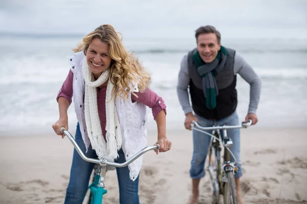 Pareja adulta montando bicicletas en la playa — Foto de Stock