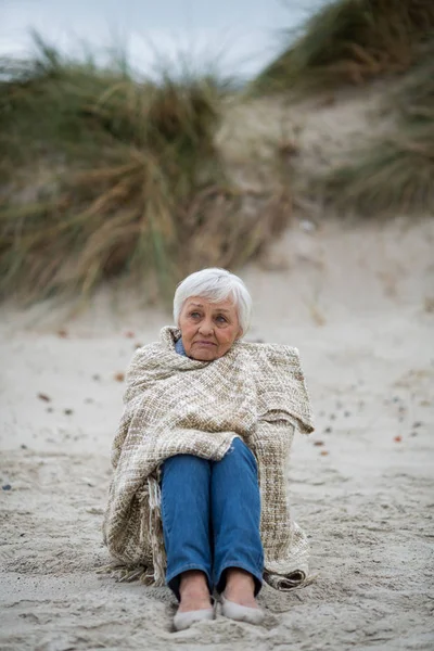 Mujer mayor envuelta en chal en la playa —  Fotos de Stock
