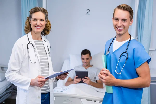 Médicos de pé com relatórios e paciente usando comprimido digital em segundo plano — Fotografia de Stock