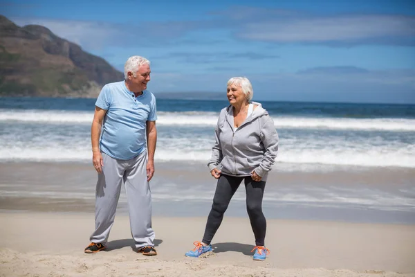 年长的夫妇做伸展运动在沙滩上 — 图库照片