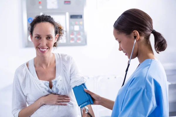 Врач проверяет кровяное давление беременной женщины — стоковое фото