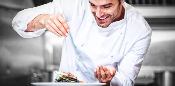 Chef sprinkling spices on dish — Stock Photo, Image