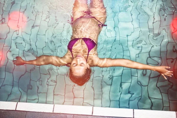 Mujer embarazada flotando en la piscina — Foto de Stock