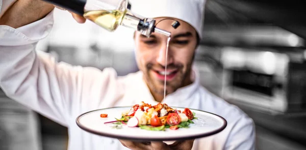 Красивый шеф-повар наливает оливковое масло на еду — стоковое фото