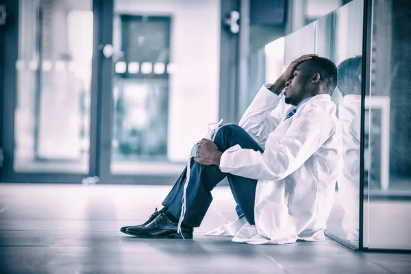 Тривожний лікар сидить на підлозі — стокове фото