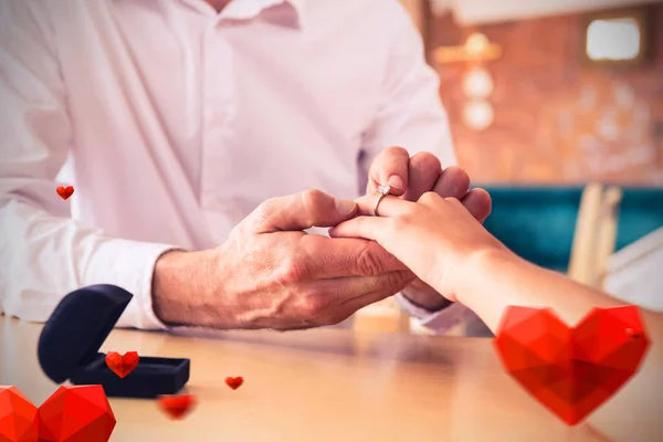 Man putting engagement ring on woman's finger — Stock Photo, Image