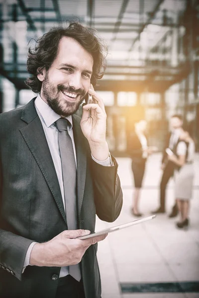 Uomo d'affari in possesso di tablet parlando al telefono — Foto Stock