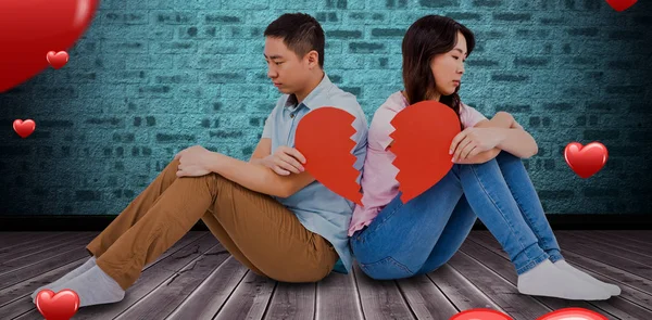 Triste casal segurando pedaços de coração quebrado — Fotografia de Stock