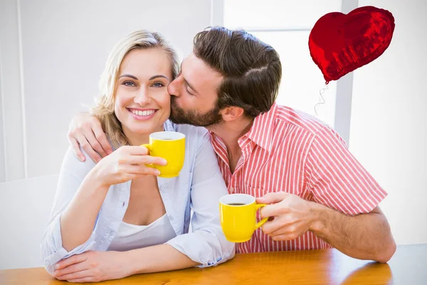 Мужчина целует женщину за чашкой кофе — стоковое фото