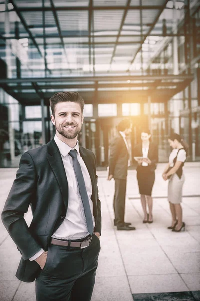 Businessman smiling with hands in pockets — Stock Photo, Image