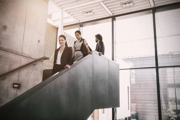 Деловая женщина с коллегами спускается по лестнице — стоковое фото