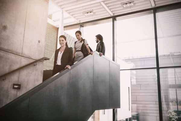 Businesswoman with colleagues climbing down stairs — Stock Photo, Image